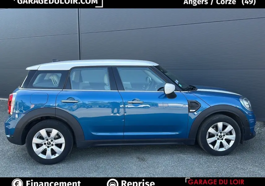 Vue de profil côté gauche d'une MINI Countryman Cooper bleu avec toit blanc et jantes argentées sur fond gris.