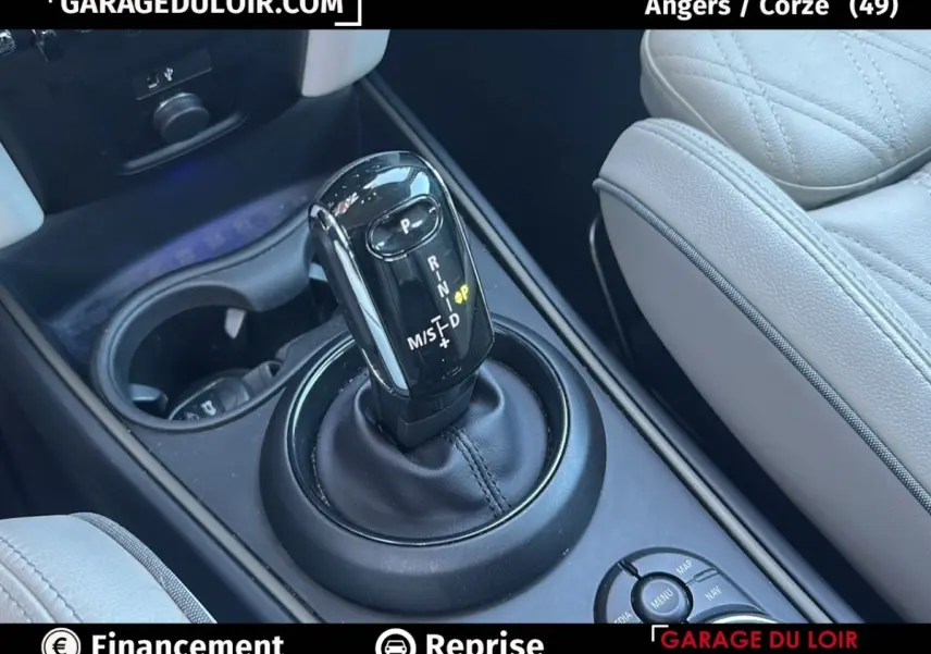 Gros plan sur le levier de vitesses automatique noir et la console centrale, avec siège en cuir beige visible à droite.
