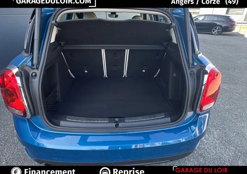 Coffre ouvert d'une MINI Countryman Cooper bleu, vue arrière mettant en valeur l'espace de chargement et les feux arrière rouges.