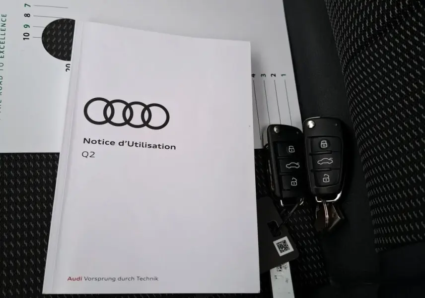 Gros plan sur la porte intérieure côté conducteur noire de l'Audi Q2 2023 avec commandes de vitres et rétroviseurs.