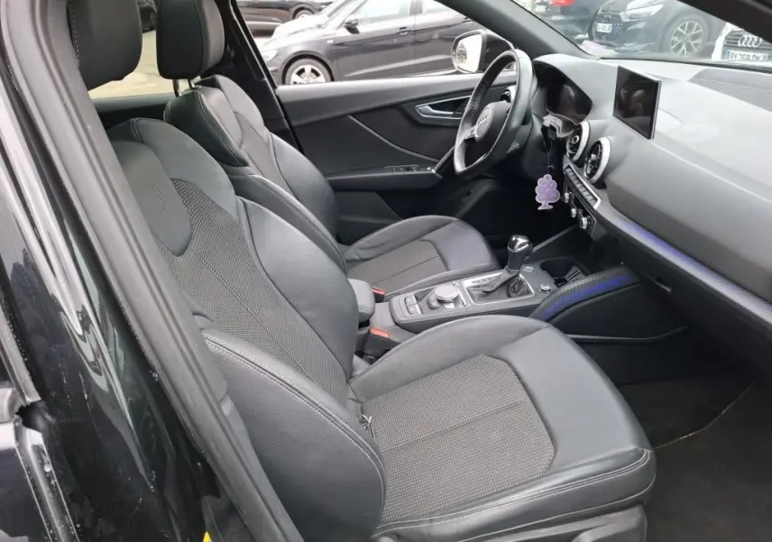 Vue intérieure côté conducteur de l'Audi Q2 noir 2023, sièges sport en cuir avec logo S embossé sur appuie-têtes.