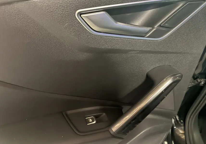 Détail de la porte intérieure côté conducteur noire de l'Audi Q2 2023 avec poignée et bouton de verrouillage électrique.