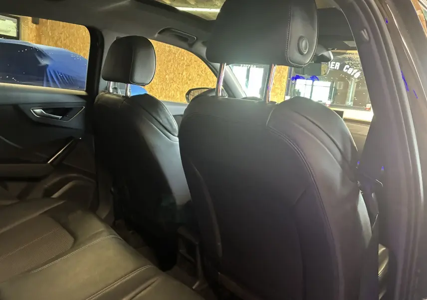 Vue intérieure arrière de l'Audi Q2 2023 noir, montrant les sièges avant et banquette arrière en cuir noir.