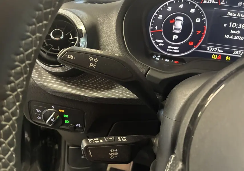 Vue rapprochée du tableau de bord noir d’un Audi Q2 2023, avec commandes au volant et affichage numérique du compteur.