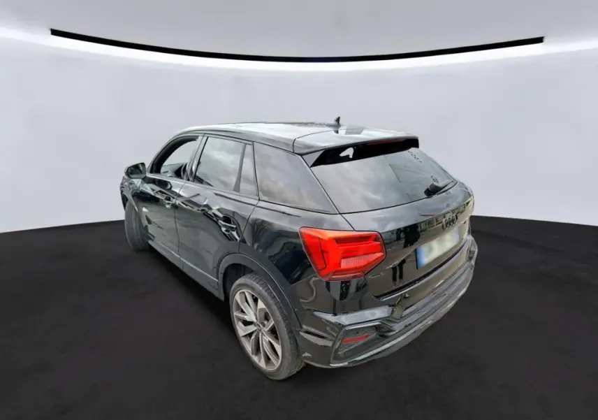 Audi Q2 noir vue de profil côté gauche, avec jantes alliage et intérieur visible à travers les vitres teintées.