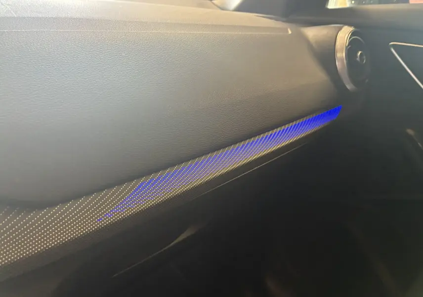 Détail de l'intérieur de l'Audi Q2 2023, vue du tableau de bord côté passager avec éclairage d'ambiance bleu.