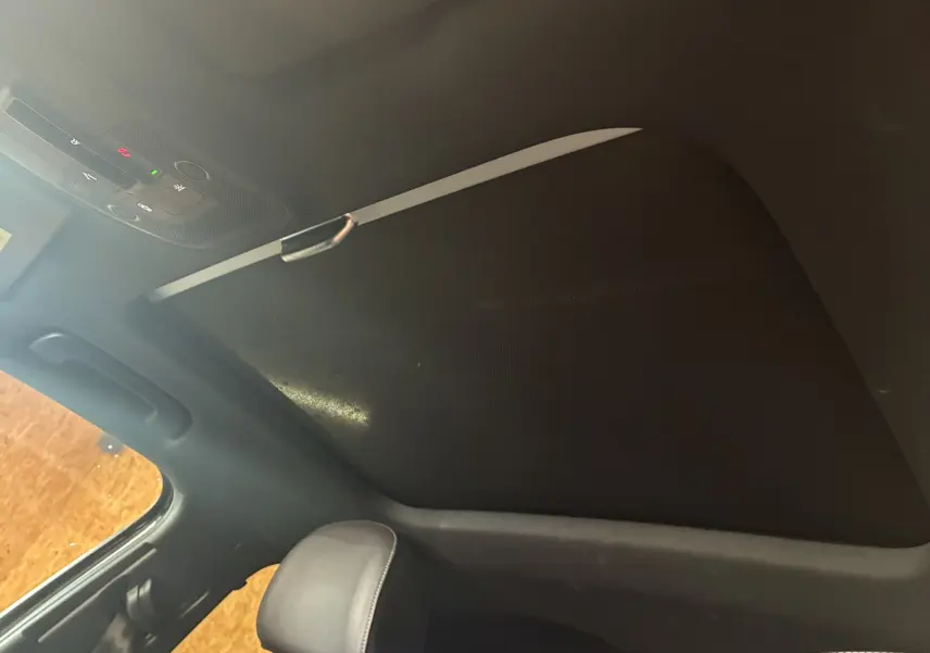 Toit ouvrant fermé et ciel de toit noir à l'intérieur de l'Audi Q2 2023, avec appuie-tête en cuir visible.