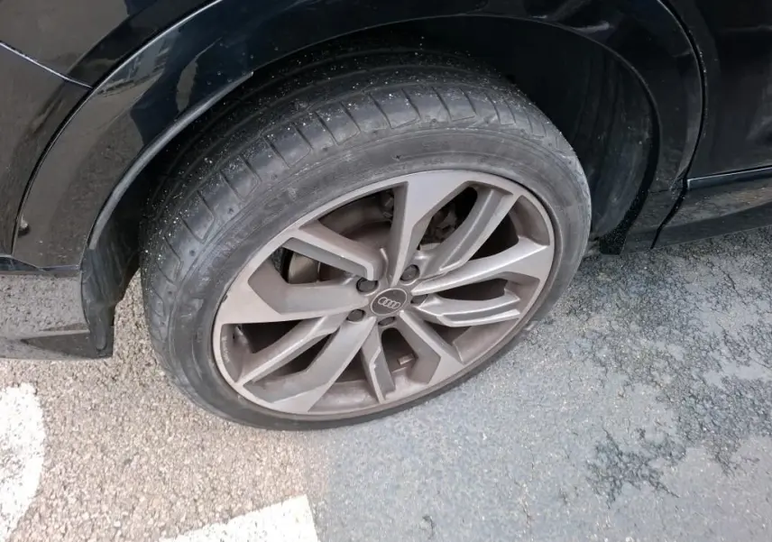 Audi Q2 noir vue de profil côté gauche, jantes alliage distinctives, stationné en intérieur avec mur en bois.