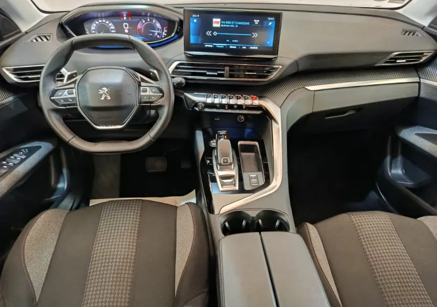 Vue intérieure avant du Peugeot 3008 gris foncé 2022, avec tableau de bord digital et écran tactile central lumineux.
