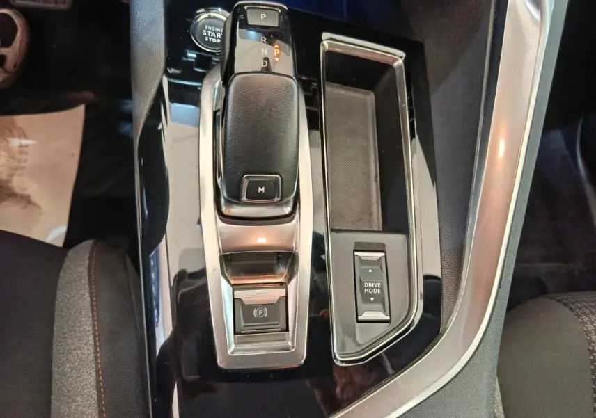 Gros plan sur la console centrale noire brillante du Peugeot 3008 gris foncé, avec levier de vitesse et commande Drive Mode.