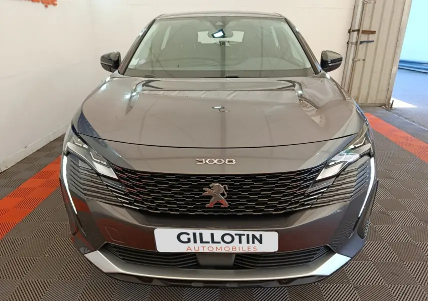 Vue avant d’un Peugeot 3008 gris foncé avec calandre noire et phares LED distinctifs, en intérieur showroom.