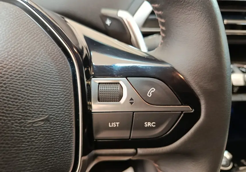 Gros plan sur les commandes multifonctions à gauche du volant cuir du Peugeot 3008 gris foncé, version 2022.