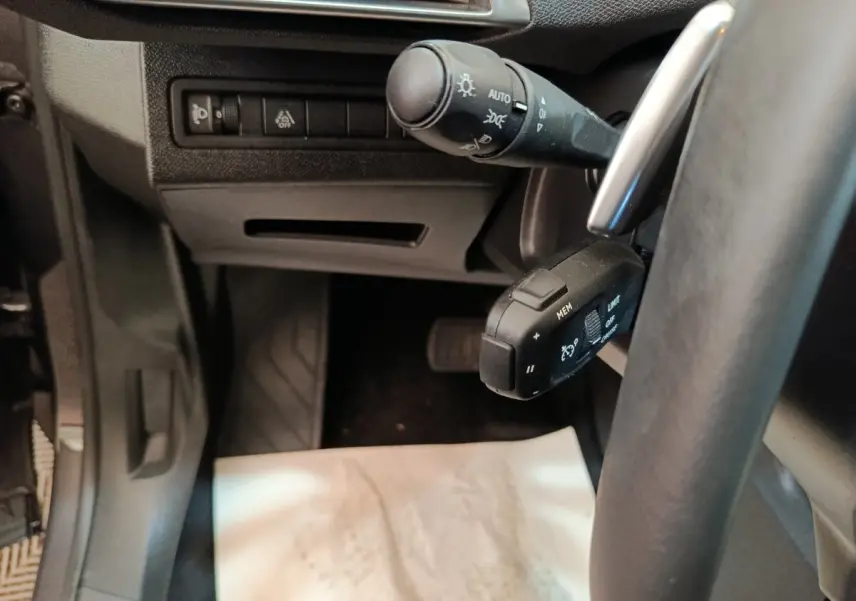 Vue rapprochée côté gauche du volant du Peugeot 3008 gris foncé, montrant les commandes de phares et régulateur de vitesse.