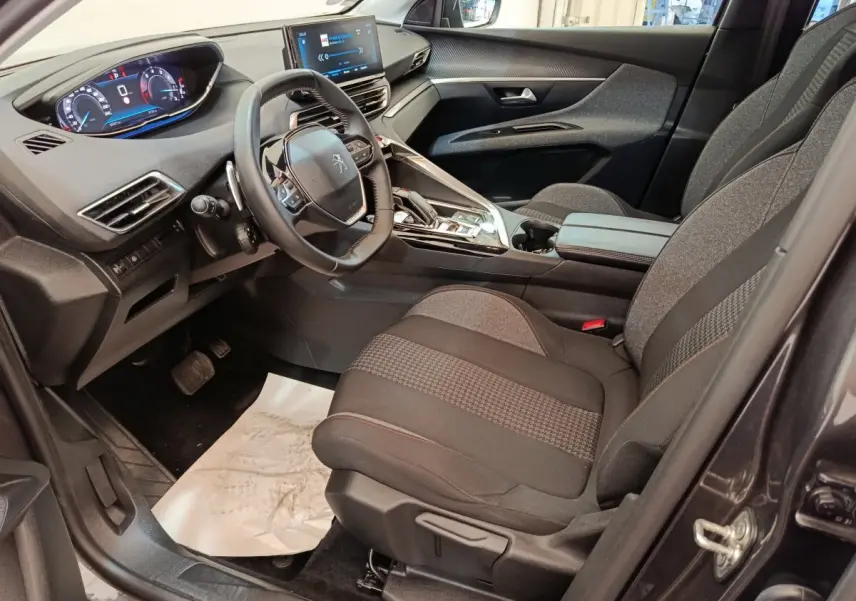 Intérieur côté conducteur du Peugeot 3008 gris foncé 2022, avec tableau de bord digital et volant cuir multifonctions.