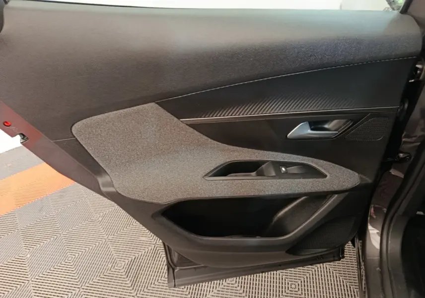 Porte intérieure côté droit de Peugeot 3008 gris foncé, avec habillage tissu et plastique noir, poignée argentée.