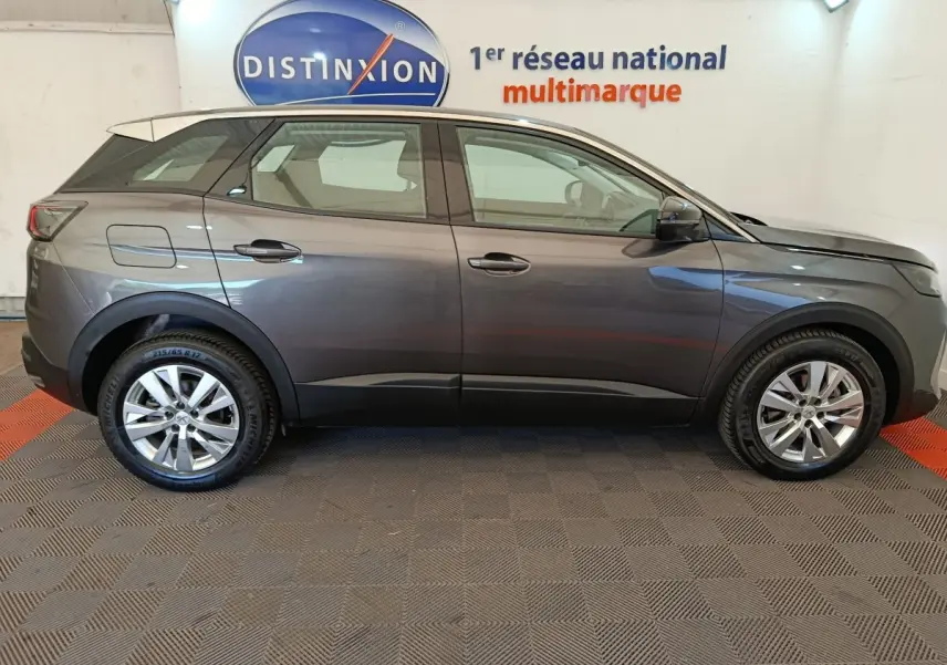 Profil latéral droit d'un Peugeot 3008 gris foncé 2022 garé en intérieur sur sol damier, avec logo Distinxion en arrière-plan.