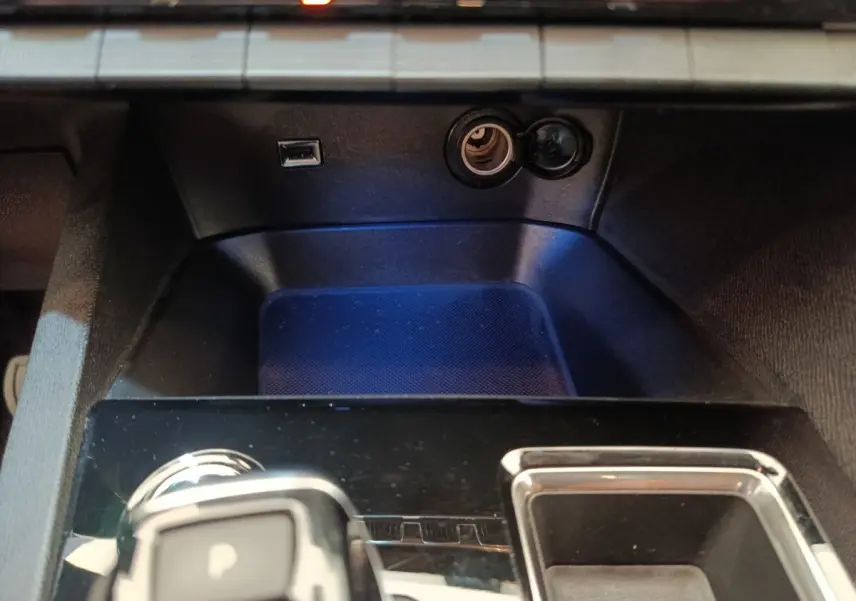 Gros plan sur la console centrale noire du Peugeot 3008 gris foncé, avec prise USB et allume-cigare visibles.