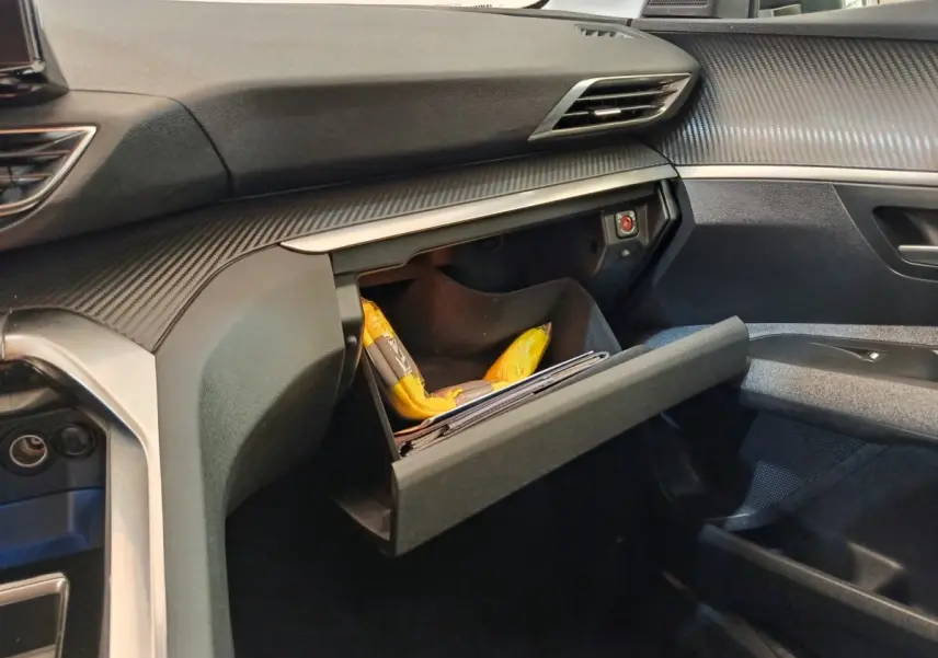 Intérieur côté passager du Peugeot 3008 gris foncé 2022, avec boîte à gants ouverte et tableau de bord texturé.