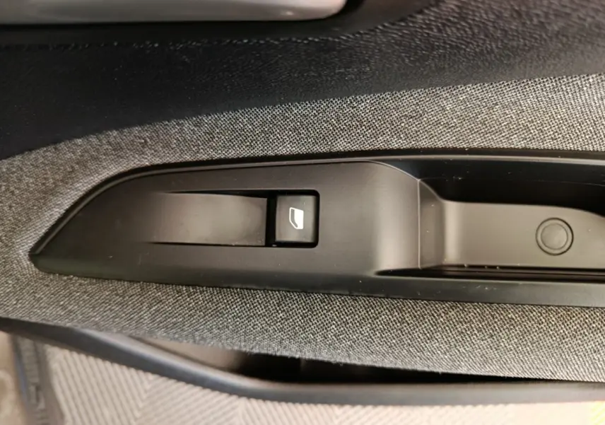 Gros plan sur la commande de lève-vitre côté passager intérieur du Peugeot 3008 gris foncé, tissu gris visible.