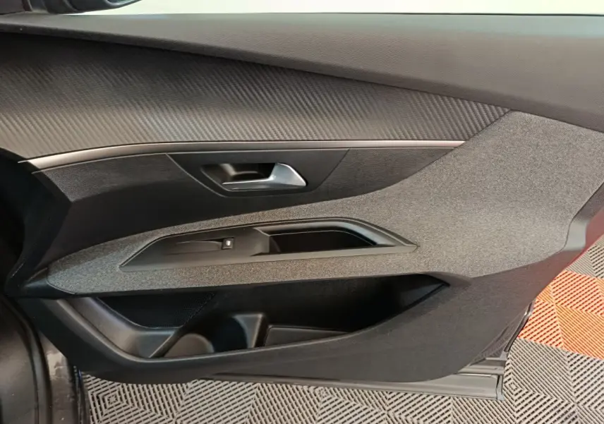 Vue intérieure côté gauche de la porte avant d'un Peugeot 3008 gris foncé avec habillage tissu et plastique noir.
