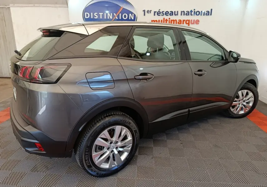 Peugeot 3008 gris foncé vue 3/4 arrière droit, avec feux arrière LED et jantes alliage visibles en intérieur showroom.