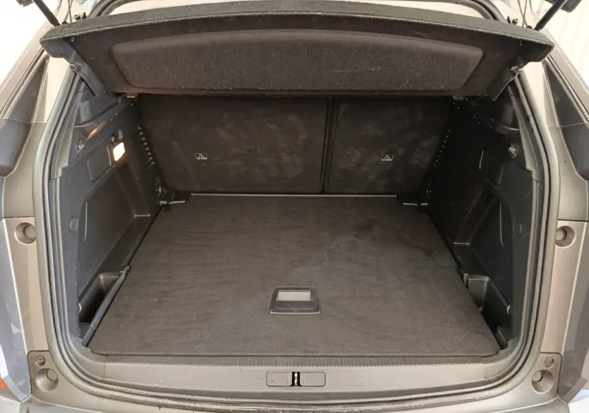 Coffre ouvert d’un Peugeot 3008 gris foncé, vue arrière montrant l’espace de chargement vide et la tablette de séparation.