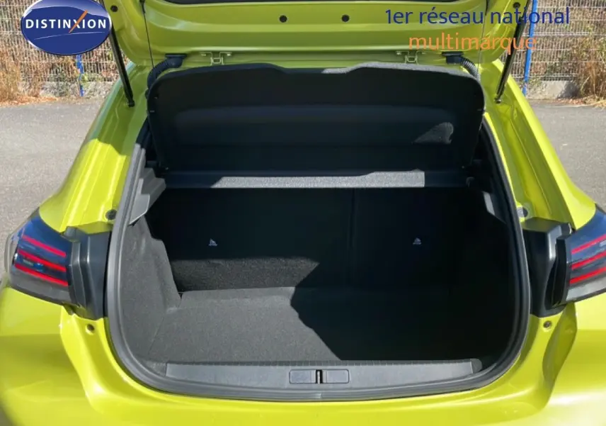 Coffre ouvert vu de l'arrière d'une Peugeot 208 Hybrid 110ch Allure en jaune Agueda métal, montrant l'espace de chargement vide.