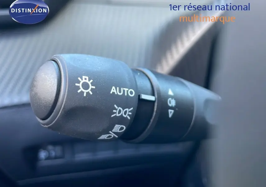 Gros plan sur la commande des phares du Peugeot 208 jaune Agueda Metal, avec réglage automatique visible.