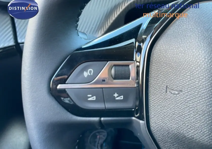 Gros plan sur les commandes de volume au volant d'une Peugeot 208 Hybrid 110ch Allure, intérieur noir.