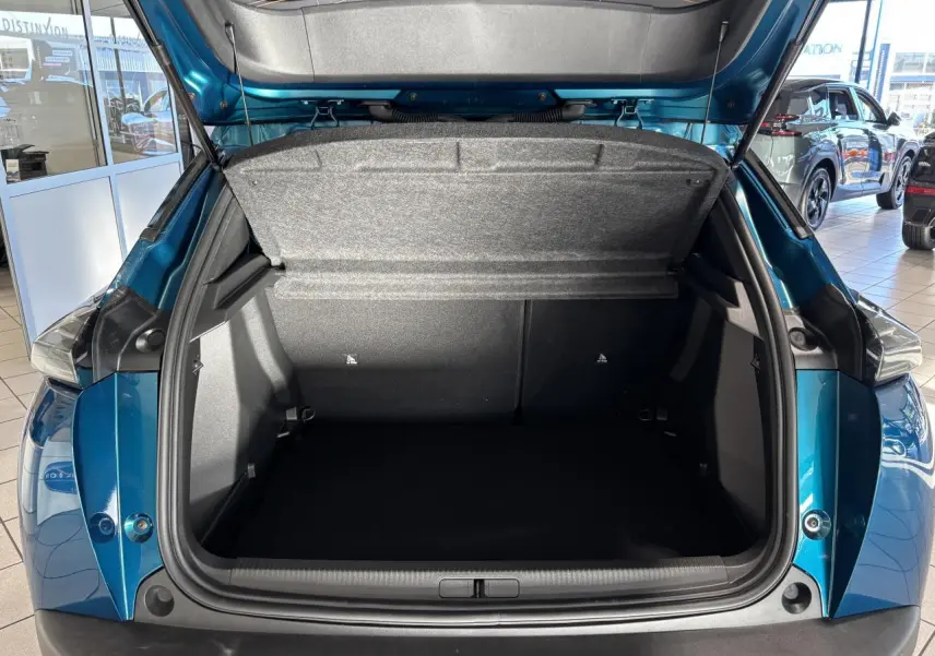 Coffre ouvert vu de l'arrière du Peugeot 2008 bleu, montrant l'espace de chargement et la trappe intérieure grise.