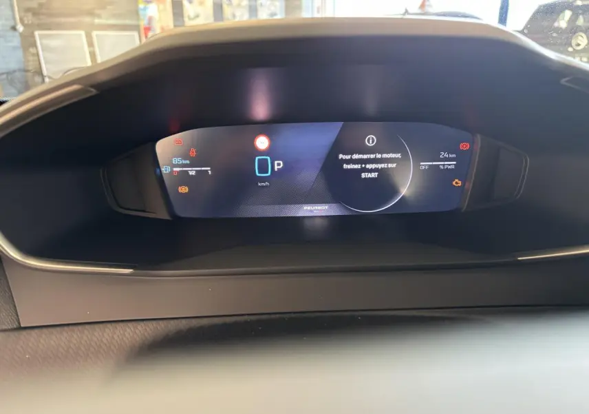 Vue rapprochée du combiné numérique 10 pouces du Peugeot 2008 Hybrid 2026 affichant les alertes et la vitesse à l'arrêt.
