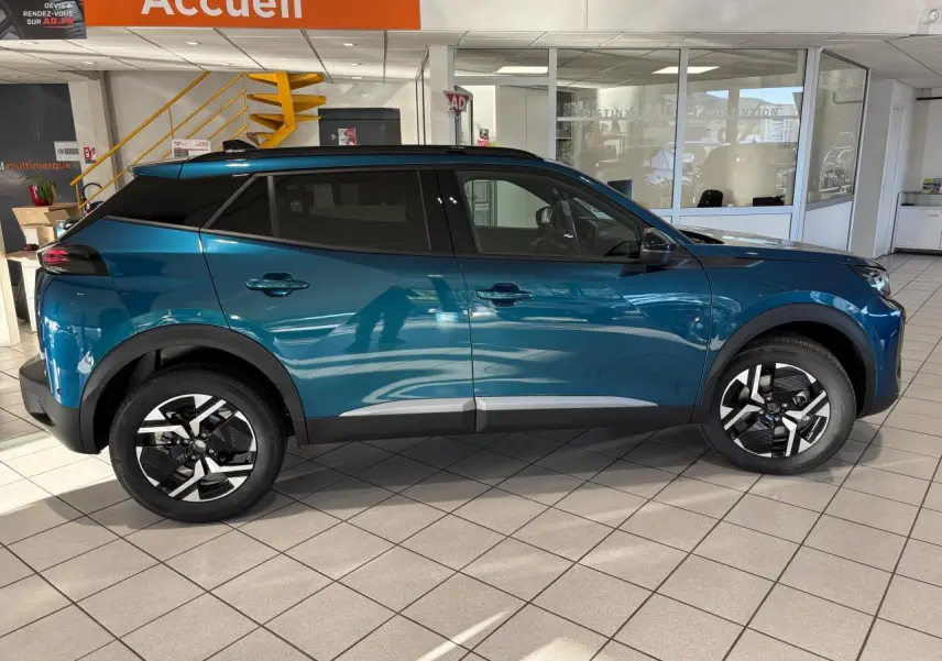 Vue latérale droite du Peugeot 2008 hybride bleu avec jantes alliage bi-ton et protections noires sur les passages de roue.