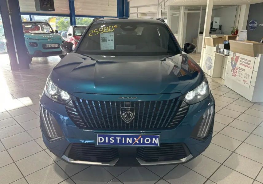 Vue avant d'un Peugeot 2008 bleu métallisé en showroom avec calandre noire et feux LED allumés.