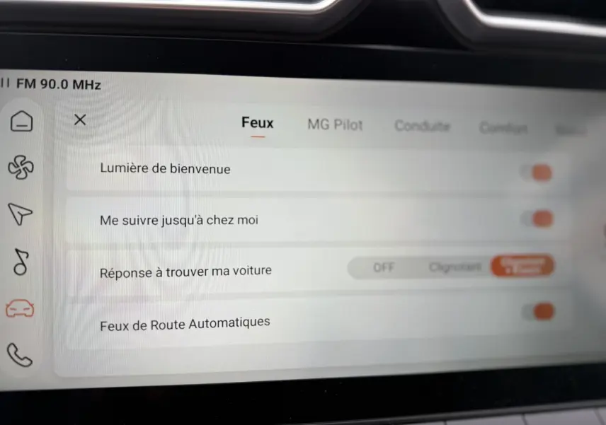 Écran tactile intérieur du MG Motor ZS 2026 montrant les réglages des feux avec interface claire et icônes latérales.
