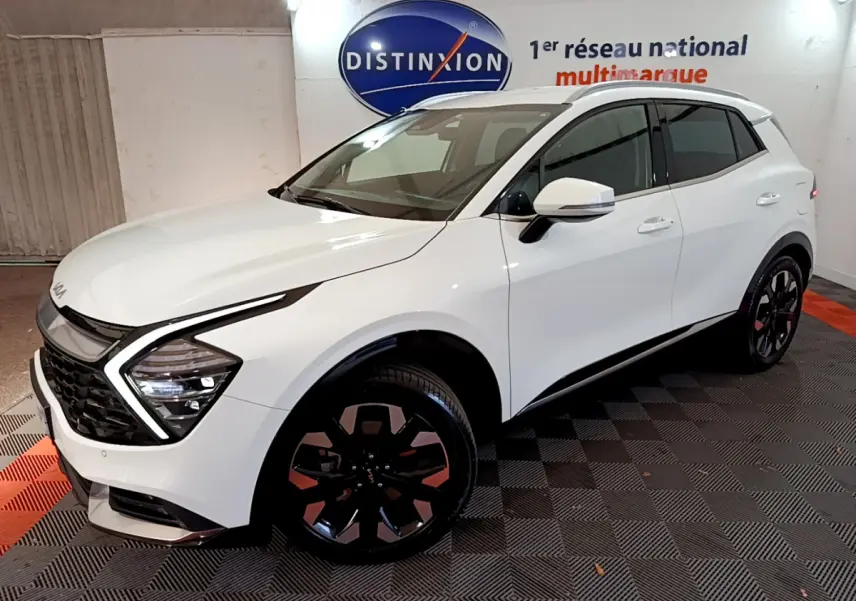KIA SPORTAGE blanc en vue 3/4 avant droit, avec phares LED en forme de flèche et jantes noires distinctives.