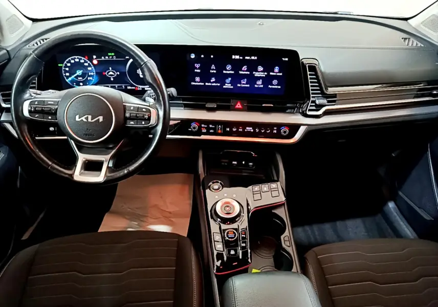 Vue intérieure frontale du tableau de bord et volant cuir noir du Kia Sportage hybride rechargeable 2022 avec écran tactile 12,3 pouces.