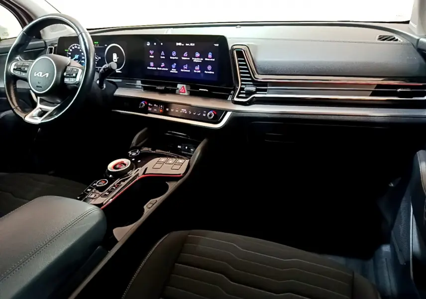 Vue intérieure côté conducteur du tableau de bord noir du Kia Sportage 2022 avec écran tactile et volant cuir multifonctions.