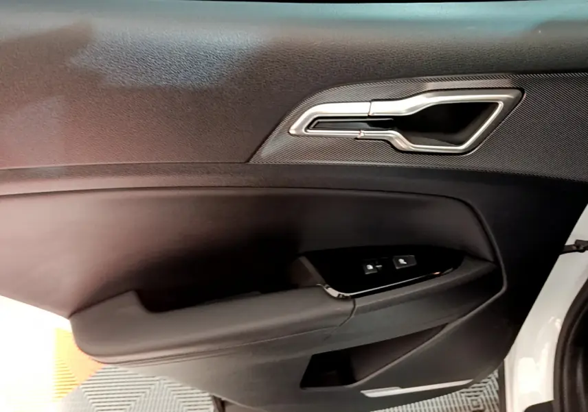 Poignée intérieure côté conducteur noire avec insert argenté sur la portière d'un KIA SPORTAGE blanc 2022 hybride rechargeable.
