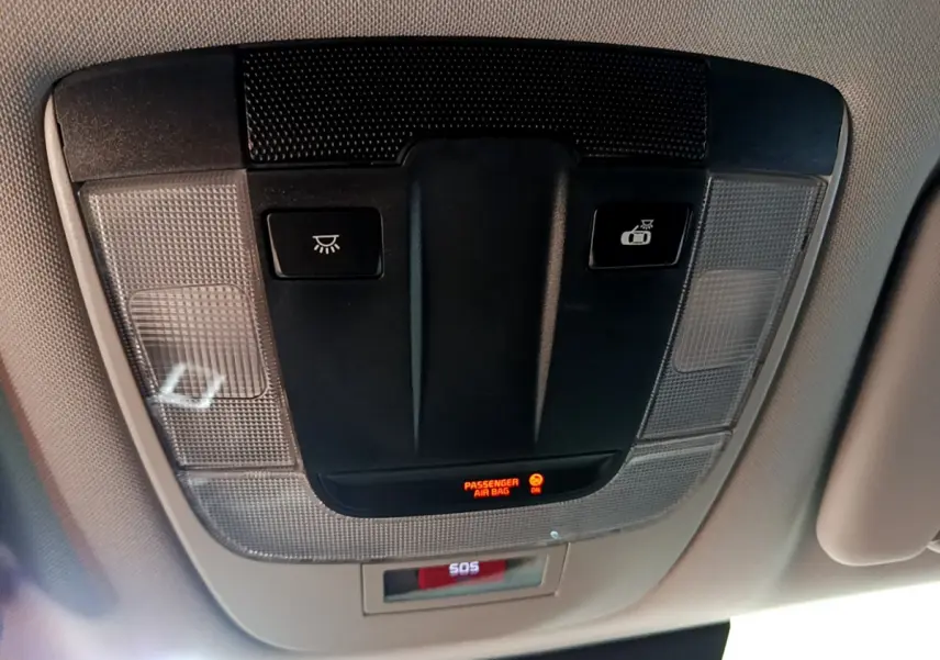 Vue rapprochée du panneau de commande au plafond intérieur du Kia Sportage blanc 2022 avec bouton SOS et indicateur airbag passager.