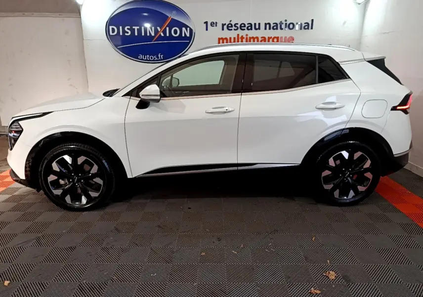 Profil côté gauche du KIA SPORTAGE blanc hybride rechargeable 2022 avec jantes noires et feux arrière LED distinctifs.