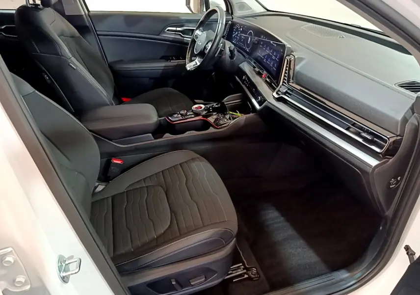 Intérieur avant droit du Kia Sportage blanc 2022, sièges noirs, tableau de bord digital et console centrale moderne.