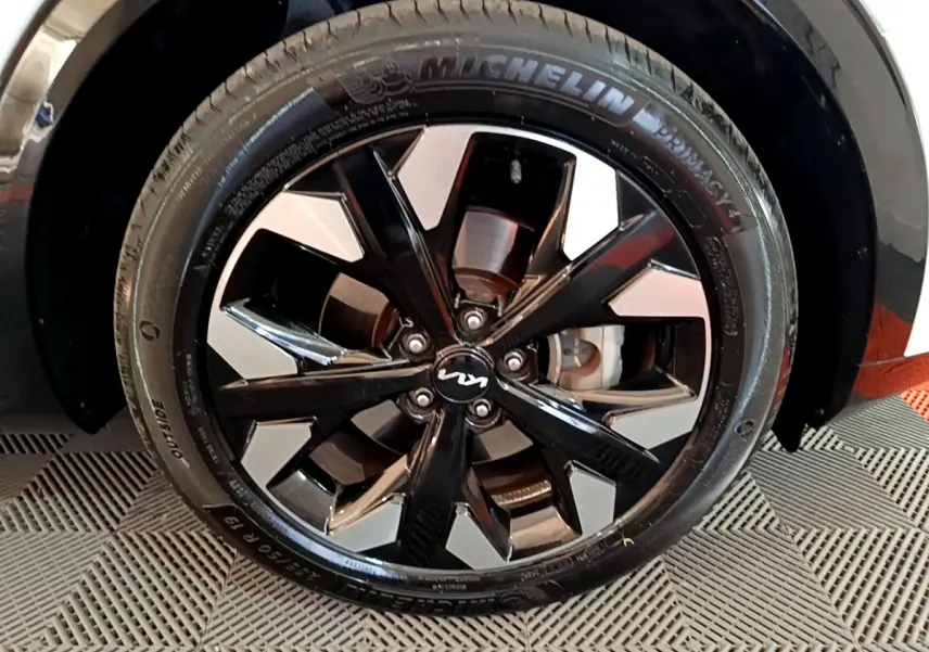 Gros plan sur la jante noire et argentée avec logo KIA du Kia Sportage blanc, mettant en valeur le pneu Michelin.
