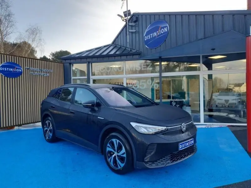 Volkswagen ID.4 148ch Pure 52 kWh Life Plus noir Ebène, vue 3/4 avant droit sur parking bleu devant concession.