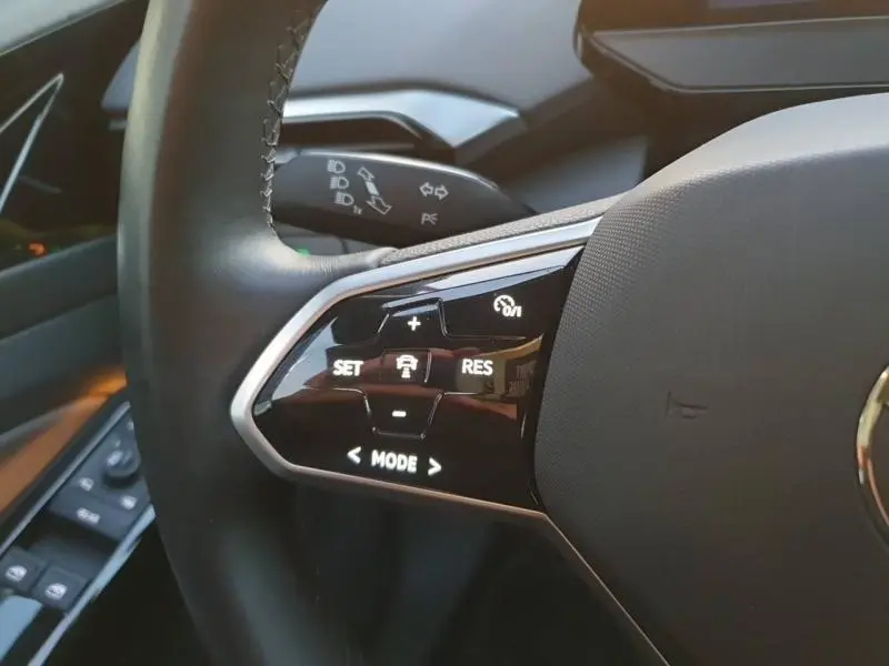 Gros plan sur les commandes du volant noir du Volkswagen ID.4 2023, avec boutons de régulateur de vitesse et mode de conduite.