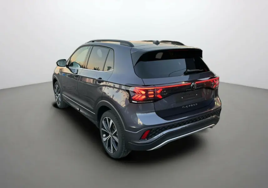Volkswagen T-Cross TSI 116 DSG7 R-Line gris cendré, vue 3/4 arrière droit avec feux arrière allumés et jantes 18 pouces.