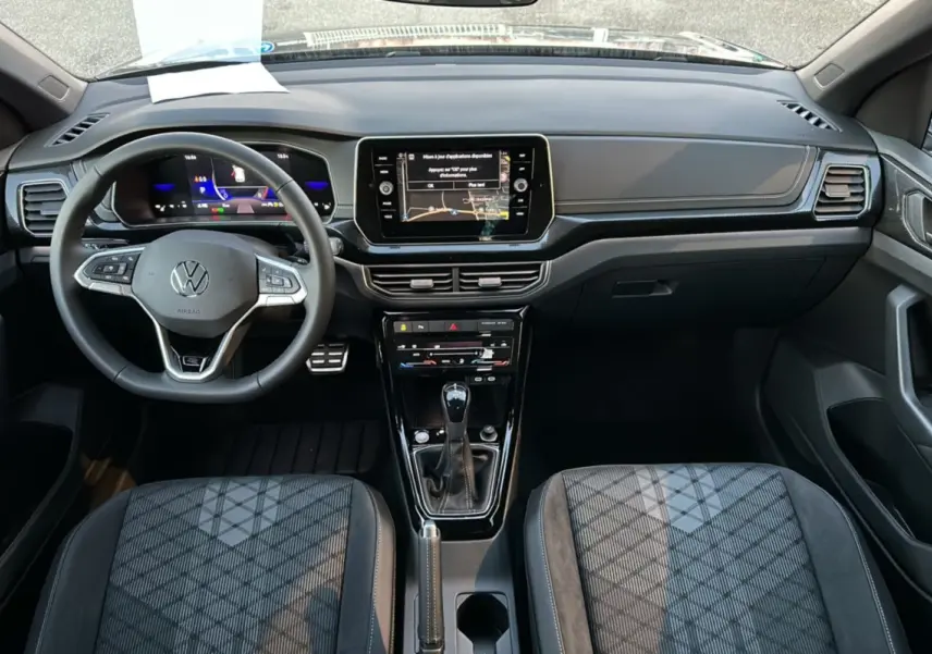 Vue intérieure avant du Volkswagen T-Cross gris cendré, tableau de bord digital et sièges tissu à motifs géométriques.