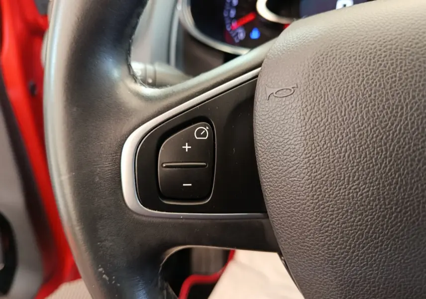 Gros plan sur le volant cuir côté gauche de la Renault Clio rouge 2018 avec commandes de régulateur de vitesse.