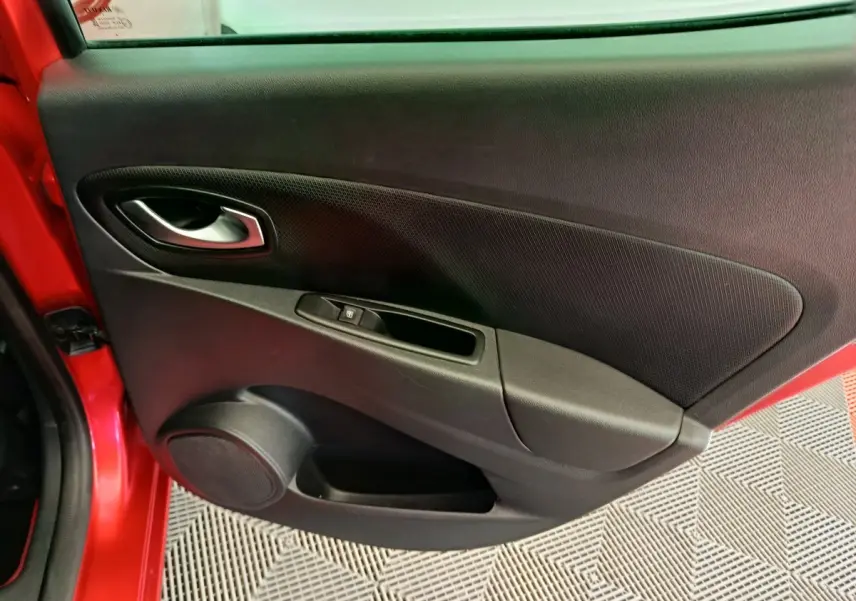Gros plan sur la porte arrière gauche rouge de la Renault Clio Intens avec habillage noir et commande de vitre électrique.