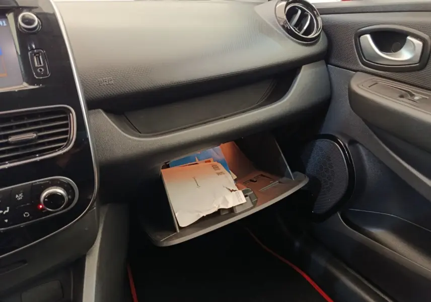 Intérieur côté passager de la Renault Clio Intens 2018, boîte à gants ouverte avec documents visibles.