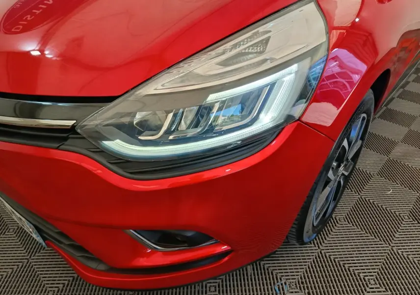 Gros plan sur l'avant droit rouge de la Renault Clio Intens 2018, mettant en valeur le phare LED et la jante noire.